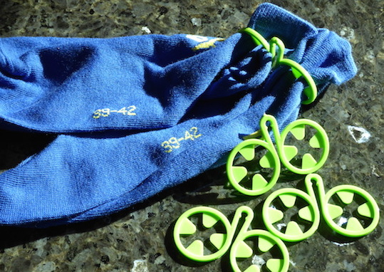 Grüner Sockenclip hält zwei blaue Socken zusammen. Ordnungshelfer.