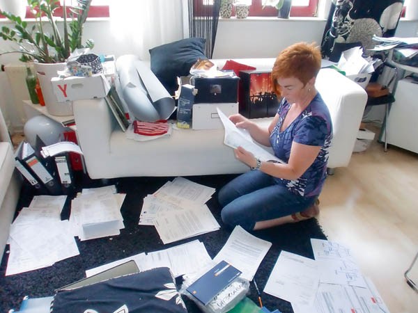 Die Ordnungsschafferin Heike Eberle kniet am Boden und sortiert mittendrin im Chaos Papiere. Wie arbeite ich?