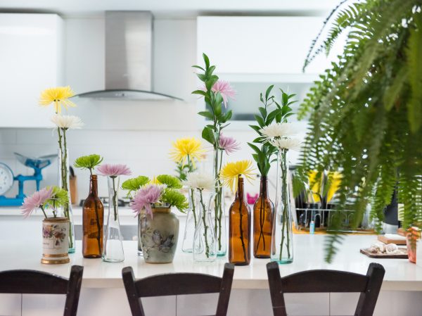 Auf dem Küchentisch stehen Blumenvasen und es sieht gemütlich aus. Ordnung für Familien in der Küche.